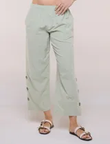 Pantalón de algodón rústico color verde, de tiro medio-alto con pretina elastizada y bolsillos laterales. Presenta corte holgado, diseño cropped de pierna ancha y aberturas laterales en los tobillos con detalles de botones.