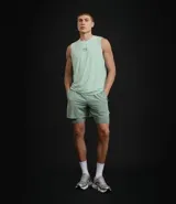 Bermuda deportiva para hombre, color verde menta, con short de compresión integrado. La bermuda exterior es suelta y tiene un pequeño logo estampado en el muslo izquierdo.
