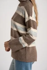 Polera de tejido de punto con diseño a rayas horizontales en tonos marrón, beige y gris. Presenta cuello alto, mangas largas con puños anchos y un corte holgado.
