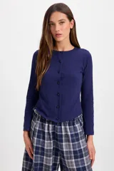 Blusa de algodón con cuello redondo, manga larga y cierre frontal con botones a tono. Presenta un diseño ajustado al cuerpo.