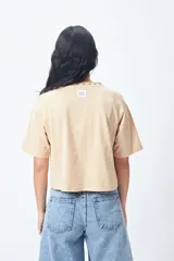 Remera blanca de manga corta con mangas ranglan y cuello redondo. El cuello tiene un bordado de estrellas negras alrededor.