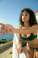 Conjunto de bikini confeccionado en tejido de lurex color verde brillante. El corpiño es tipo top cuadrado con breteles fijos y bordes en tono contrastante. La bombacha es de corte vedetina con terminaciones en zigzag y bordes a contratono.