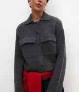Campera de punto con textura, corte recto y cuello clásico. Presenta cierre frontal con botones y dos bolsillos aplicados con solapa en el pecho.