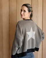 Buzo de punto color tostado con diseño de estrella grande en color crema en la espalda y bordes en color negro. Presenta un corte holgado y mangas largas.