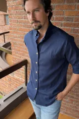 Camisa de lino color azul marino, de corte oversize, con cuello abotonado y botones en contraste. Presenta un pequeño logo bordado en el pecho.