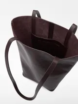 Bolso tipo shopper vertical de cuero color marrón oscuro, con asas largas para el hombro, base rígida curvada, un compartimento y bolsillo interior.