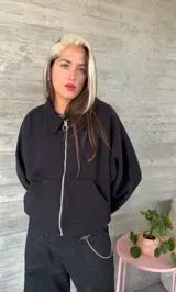 Buzo celeste de corte holgado, con cuello polo y cierre frontal parcial.