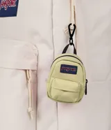 Mini mochila decorativa JanSport color negro, con bolsillo frontal y parche de la marca. Diseñada como accesorio tipo charm para colgar en bolsos o mochilas.