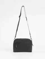 Bandolera de diseño rectangular en color verde oliva claro, con detalles de ribetes en tono rosado. Cuenta con correa ajustable, cierre principal y un bolsillo frontal con cierre, además de un pequeño aplique metálico decorativo en la parte inferior.