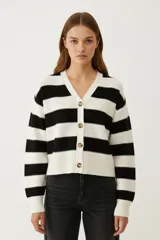 Cardigan de punto, holgado y corto, con cuello en V y cierre frontal de botones. Presenta un diseño de rayas horizontales anchas en blanco y negro.