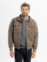 Campera de estilo bomber en tejido tipo gamuza color beige, con cuello alto, cierre frontal, bolsillos con solapa en el pecho y puños y cintura elastizados.