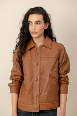 Campera de cuero marrón, con cuello camisero, cierre frontal con botones metálicos y bolsillos frontales.