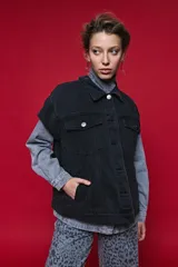 Chaleco de jean oversized color negro, con cuello camisero y cierre frontal con botones metálicos. Presenta un diseño estructurado con costuras reforzadas.