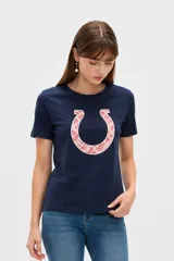 Remera azul marino de manga corta, con cuello redondo y diseño holgado. Presenta un aplique bordado frontal en forma de herradura con patrón geométrico en tonos rosados.