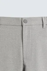Pantalón de corte slim fit confeccionado en tejido elástico, con cintura elástica, cierre frontal con cremallera y botón, bolsillos laterales y bolsillos traseros de vivo.