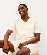 Pijama de dos piezas compuesto por camisa de manga corta con cuello solapa y cierre frontal de botones, y shorts con cintura elástica. Confeccionado en algodón de textura suave y ligera.