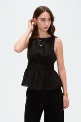 Top de lyocell color negro, sin mangas, con cuello redondo y diseño fruncido con elástico en la cintura que genera un corte peplum.