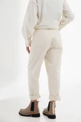 Pantalón color crudo, de corte recto, con bolsillos frontales y traseros, costuras contrastantes y cierre frontal.