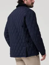 Campera acolchada azul marino con costuras en rombos, cuello de pana negro y cierre frontal con botones a presión. Incluye bolsillos laterales con ribete de pana y broches ajustables en la cintura.