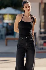 Jeans de mezclilla en color negro con efecto lavado, de tiro alto y cinco bolsillos, con perneras extra anchas y cierre frontal con cremallera y botón metálico.