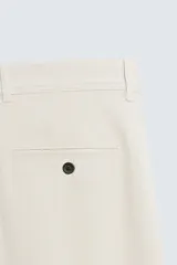 Pantalón chino de corte slim fit, confeccionado en tejido elástico. Presenta bolsillos frontales, bolsillos traseros de vivo con botón y cierre frontal con cremallera y botón.
