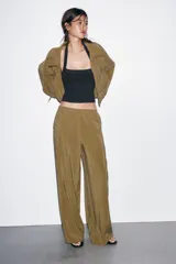 Pantalón tipo palazzo de corte recto y tejido fluido, color naranja. Presenta cintura elástica con cordón ajustable y bolsillos laterales.