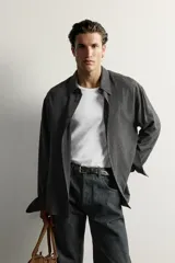 Camisa de hombre regular fit confeccionada en tejido fluido de viscosa gris, con cuello solapa, manga larga con puño abotonado y cierre frontal con botones.