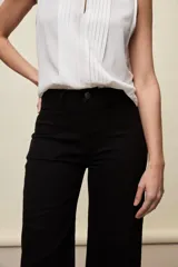 Jean wide leg negro de tiro medio confeccionado en denim con spandex, con bolsillos frontales tipo parche y silueta amplia de corte recto.