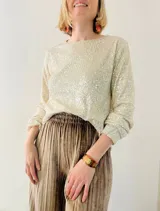 Blusa de lentejuelas color crema, de mangas largas con puños elásticos.