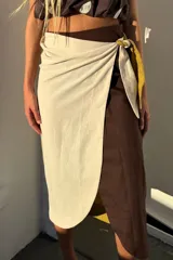 Falda envolvente tipo pareo de largo midi, confeccionada en lino. Presenta un estampado con bloques de color en tonos chocolate, pistacho y crudo.