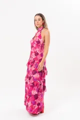 Vestido largo fucsia con estampado abstracto, cuello halter con abertura en forma de lágrima y volados en la falda.