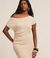 Blusa de punto color crema, con escote asimétrico, mangas cortas, textura y fruncido lateral.