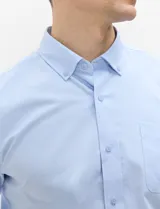 Camisa de manga larga de tejido Oxford color celeste, con cuello button-down, cierre frontal de botones y un bolsillo aplicado en el pecho.