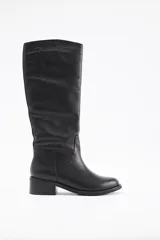 Bota de caña alta confeccionada en cuero vacuno, con taco cuadrado bajo y punta redondeada.