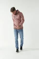 Buzo canguro color rosado con capucha ajustable con cordones, bolsillo canguro, logo estampado al frente y puños a rayas.