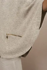 Capa con capucha, cierre frontal completo y bolsillos laterales con cierre. Presenta un diseño amplio y descontracturado, confeccionada en lana fina sin teñir.