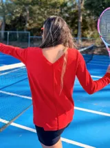 Remera de algodón color rojo con escote en V, mangas largas y diseño holgado. Presenta una costura vertical central en el frente.