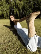 Botas de cuero color marrón y blanco con bordados negros, de estilo cowboy con taco bajo.