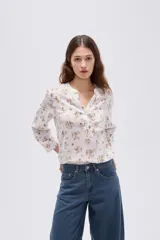 Blusa de viscosa color beige con cuello en V, cierre parcial de botones frontales, bolsillo en el pecho y mangas 3/4.
