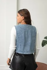 Chaleco de jean con bordados étnicos y detalles de lentejuelas en tonos azules, con corte recto y sin cierre frontal.