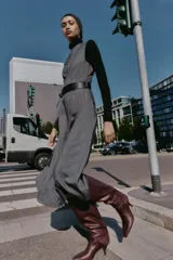 Vestido midi jaspeado en tonos grises, con cuello redondo, manga sisa y bajo en evasé. Incluye un cinturón ancho negro con hebilla rectangular y cierre de cremallera oculta en la espalda.