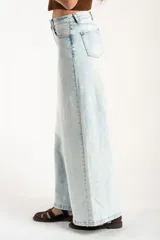 Jean de corte wide leg con tiro medio, confeccionado en denim de algodón con un lavado claro desgastado. Presenta diseño de cinco bolsillos y cierre frontal con botón y cremallera.