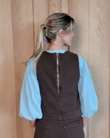 Chaleco de denim con diseño a rayas verticales, cuello redondo y corte recto. Presenta pespuntes en contraste y detalle de aberturas en los laterales.