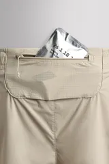 Short de running 2 en 1 color beige, confeccionado en tejido técnico ligero y elástico con malla interior integrada. Presenta cintura elástica ajustable con cordón, bolsillo trasero con cierre y aberturas laterales en el bajo.