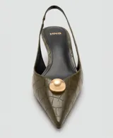 Zapatos destalonados de tacón fino y punta afilada, en color verde militar con textura efecto cocodrilo y detalle de media esfera dorada en la punta.