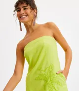 Vestido corto sin breteles color verde lima, confeccionado en lino y algodón. Presenta bolsillos laterales y bordado frontal de una palmera y conchas marinas.