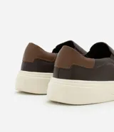 Championes tipo slip-on de cuero marrón con detalle de talón en tono contrastante y suela de goma blanca.