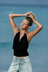 Top de poliamida color negro con escote drapeado y cuello halter que incorpora un detalle de choker metálico dorado.