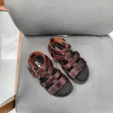 Sandalias de cuero marrón con tiras anchas y hebilla lateral.