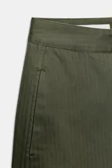 Pantalón de tiro medio con diseño barrel, pernera holgada que se estrecha hacia el tobillo, bolsillos delanteros y bolsillos de plastrón en la espalda. Confeccionado en tejido con textura de espiga, cuenta con cierre frontal de cremallera, botón interior y gancho.